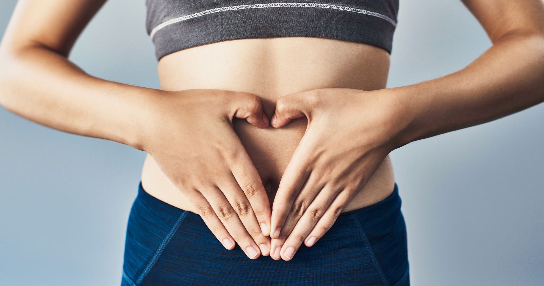Kobieta trzymająca dłonie na brzuchu w kształcie serca – symbol zdrowego metabolizmu i pracy układu trawiennego.