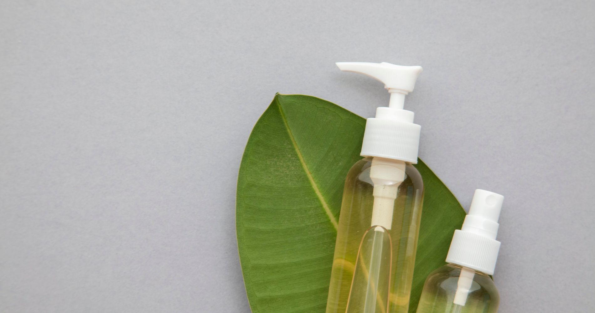 Naturalne kosmetyki organiczne w szklanych butelkach na liściu – ekologiczna pielęgnacja skóry.