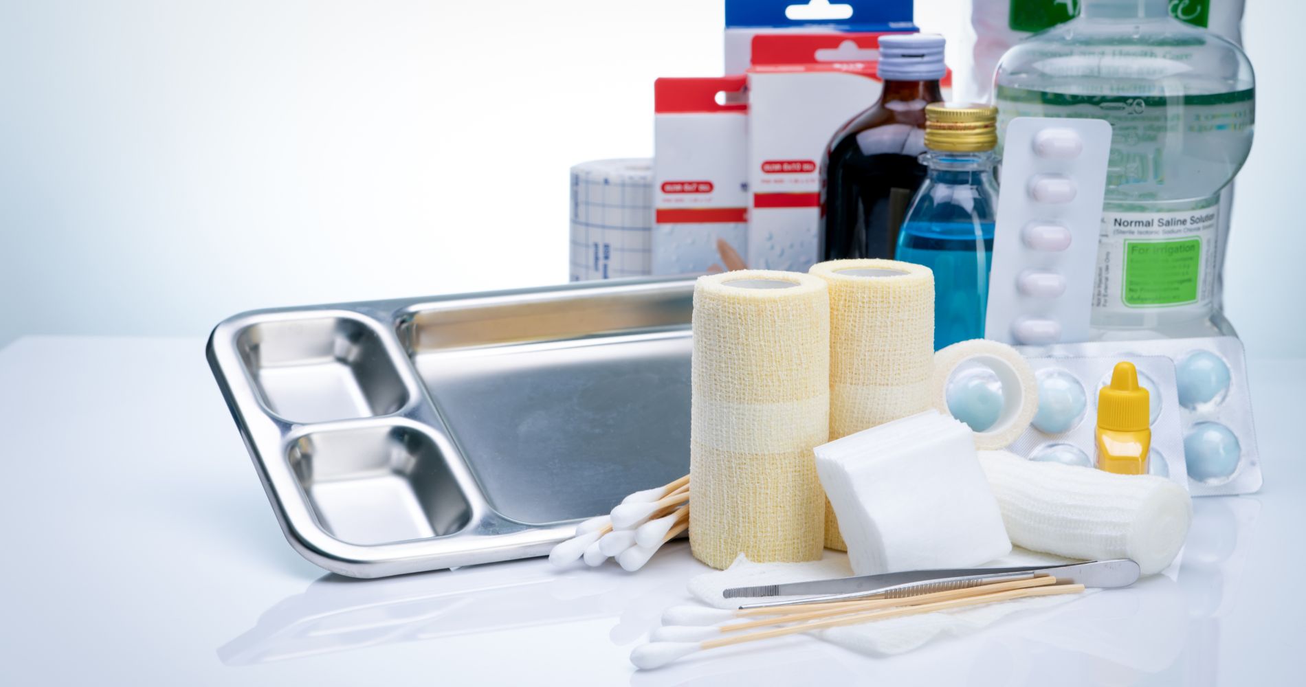 Zestaw materiałów do pielęgnacji ran: bandaże, gaziki, płyny do oczyszczania i akcesoria medyczne.