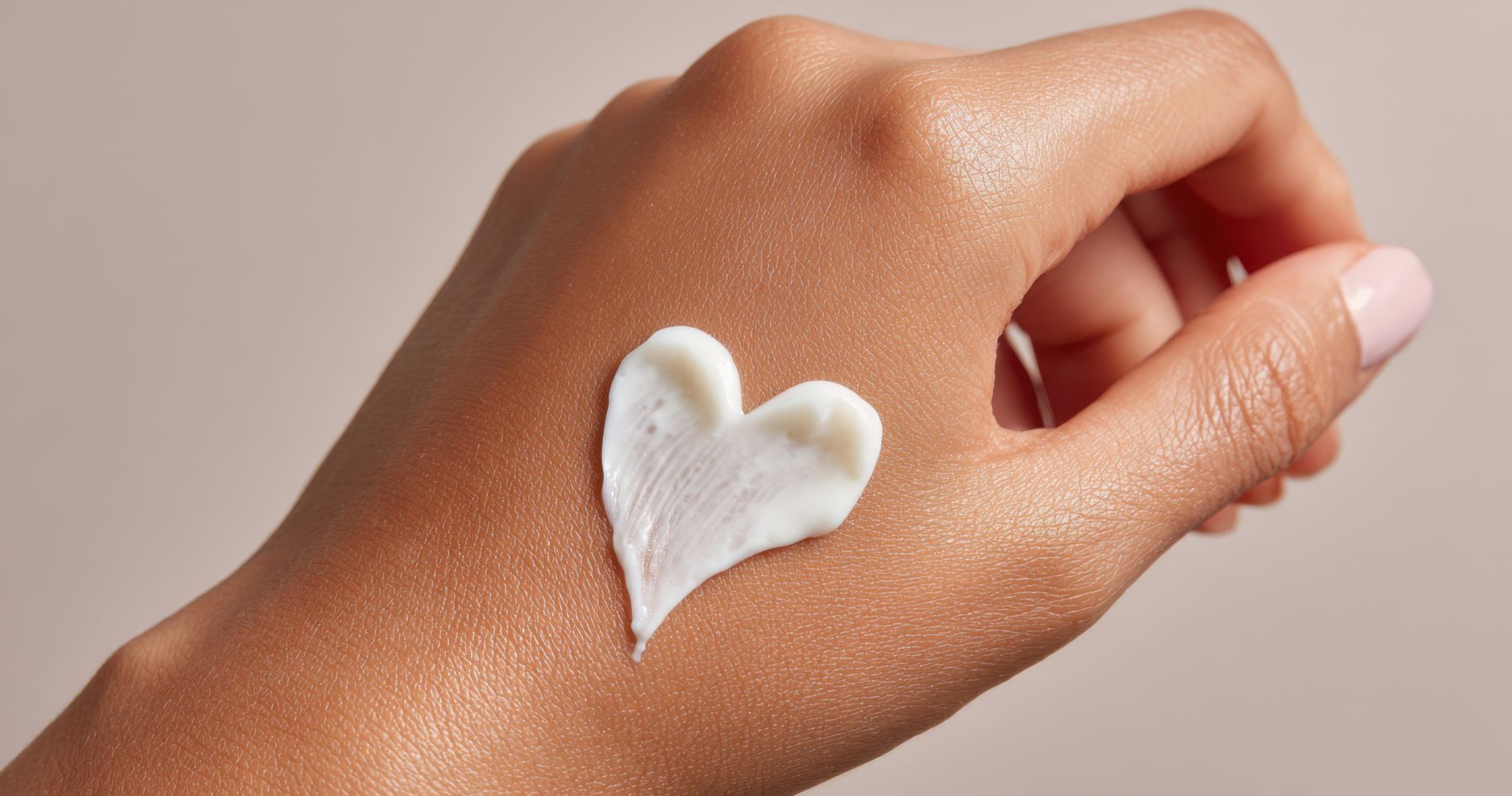 Ręka z nałożonym kremem w kształcie serca jako symbol pielęgnacji suchej skóry.