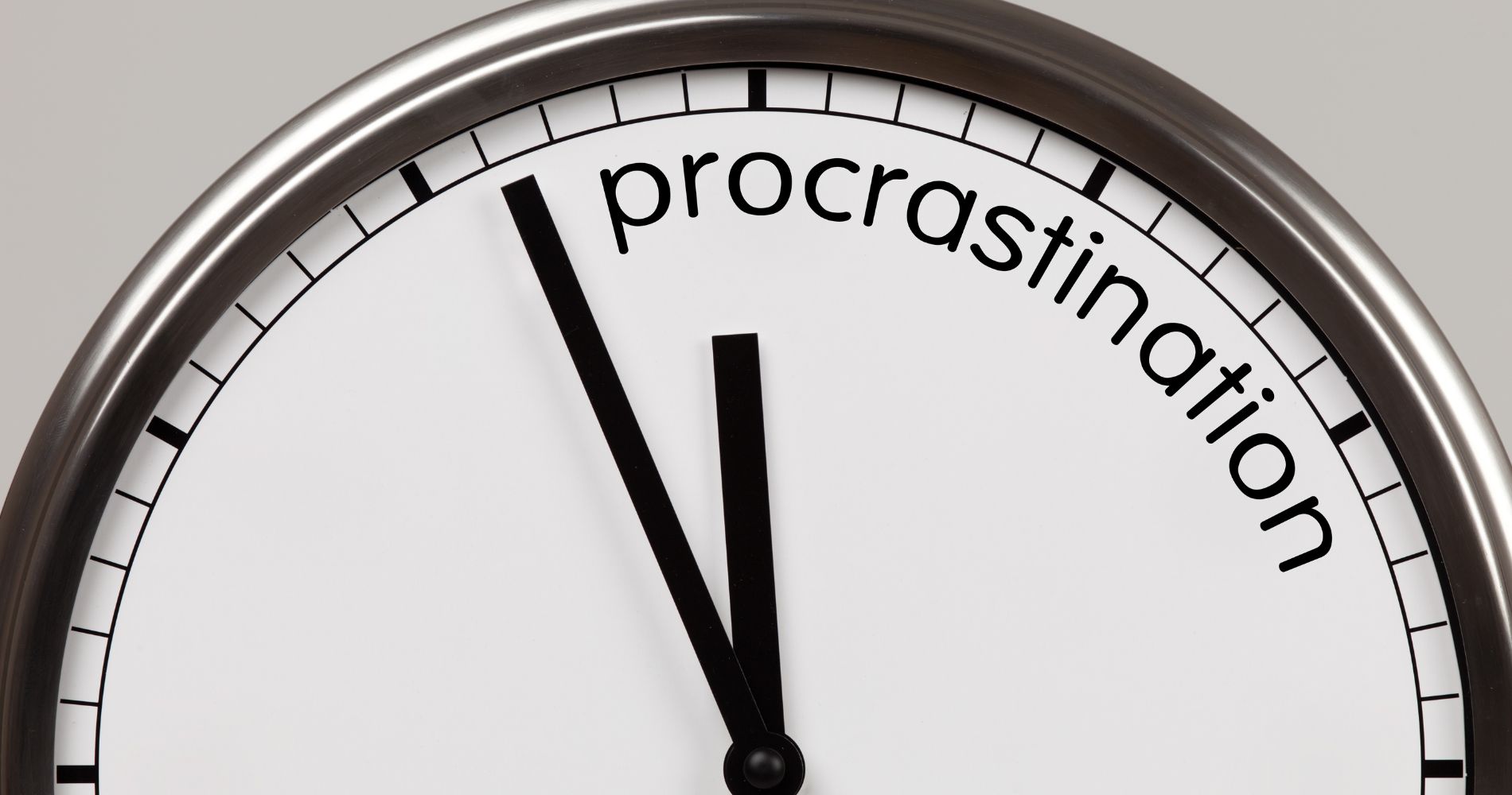 Zegar z napisem „procrastination” symbolizujący odkładanie zadań na później.