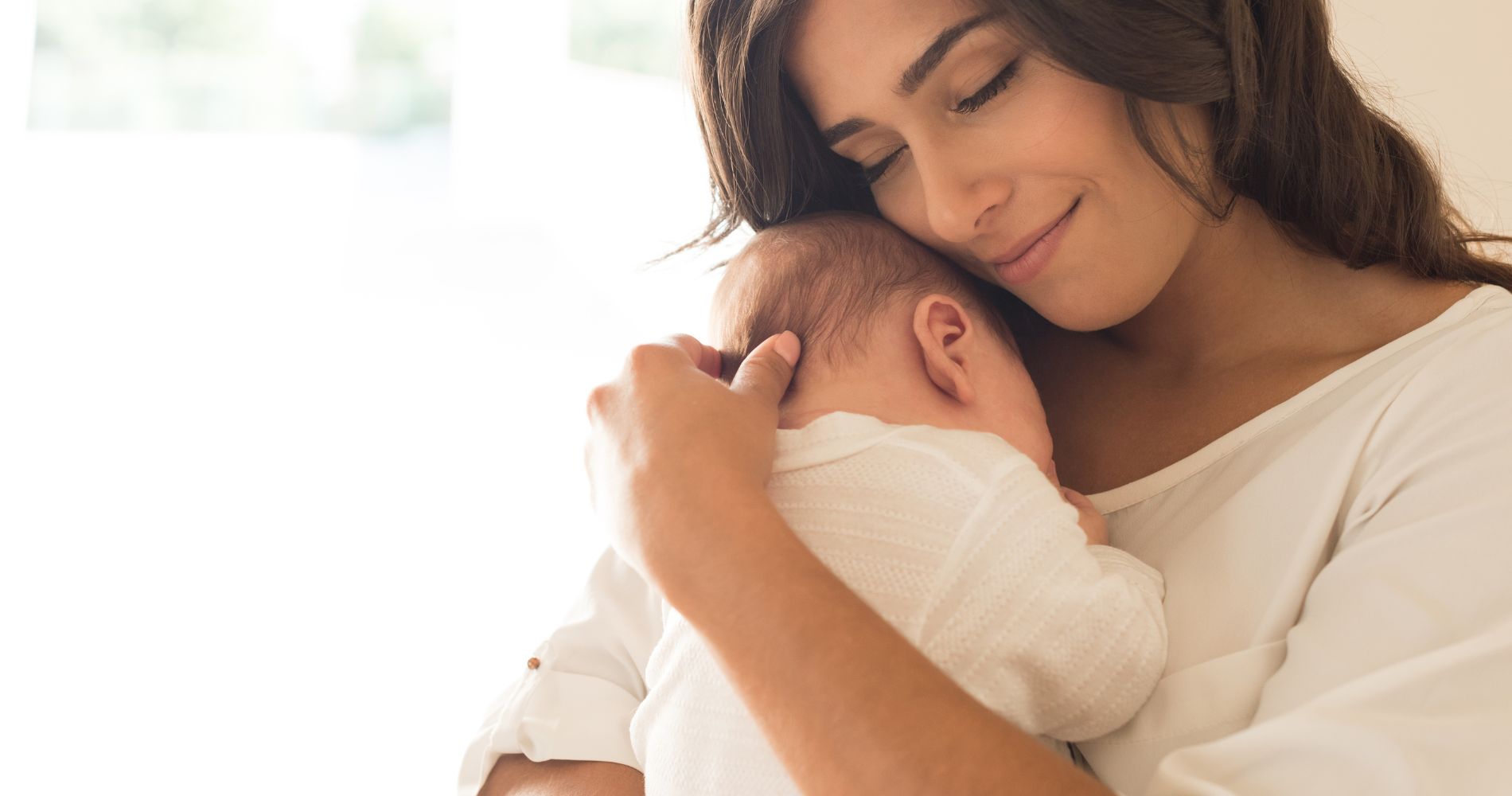 Matka tuląca noworodka podczas karmienia piersią i budowania bliskości z dzieckiem.