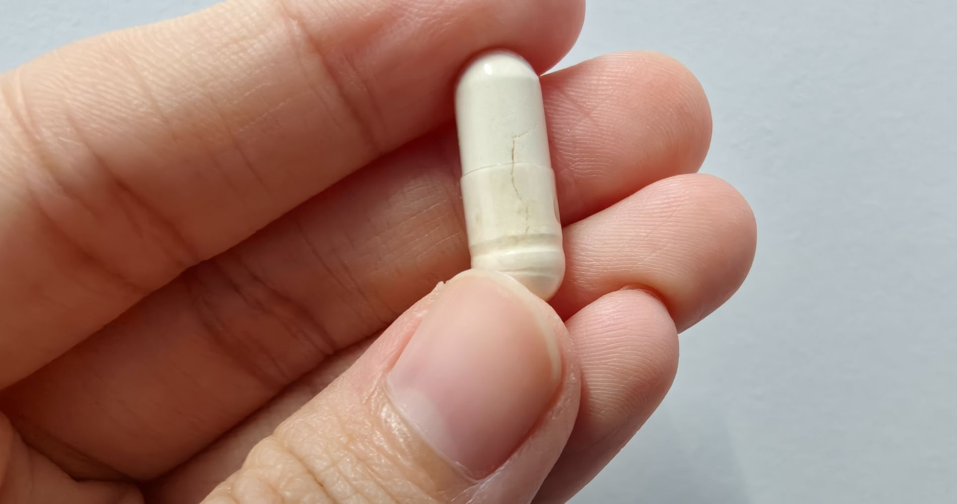 Kapsułka probiotyku trzymana w dłoni – suplement wspierający mikrobiom jelitowy.