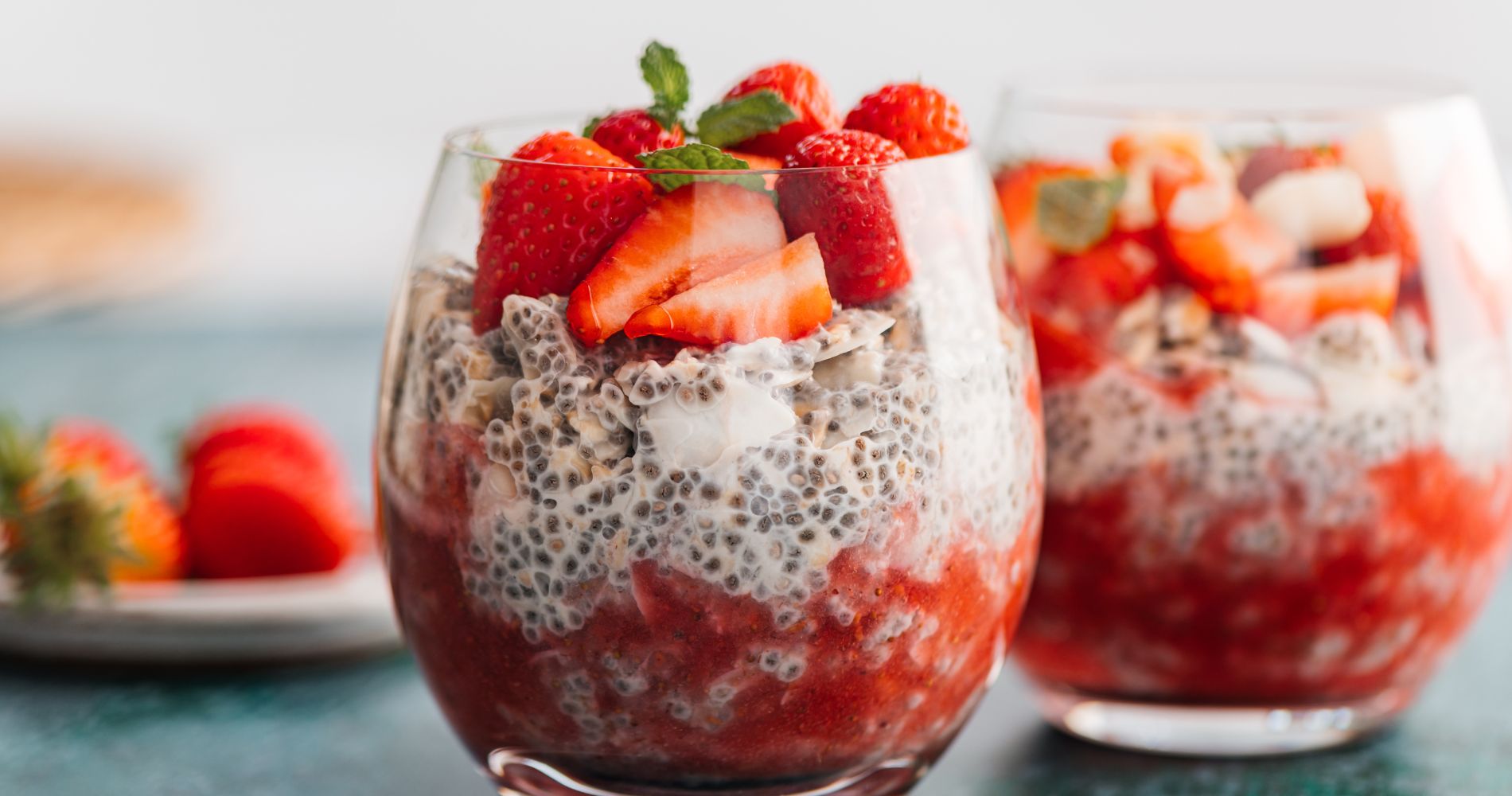 Pudding z nasion chia z truskawkami podany w szklanych naczyniach.